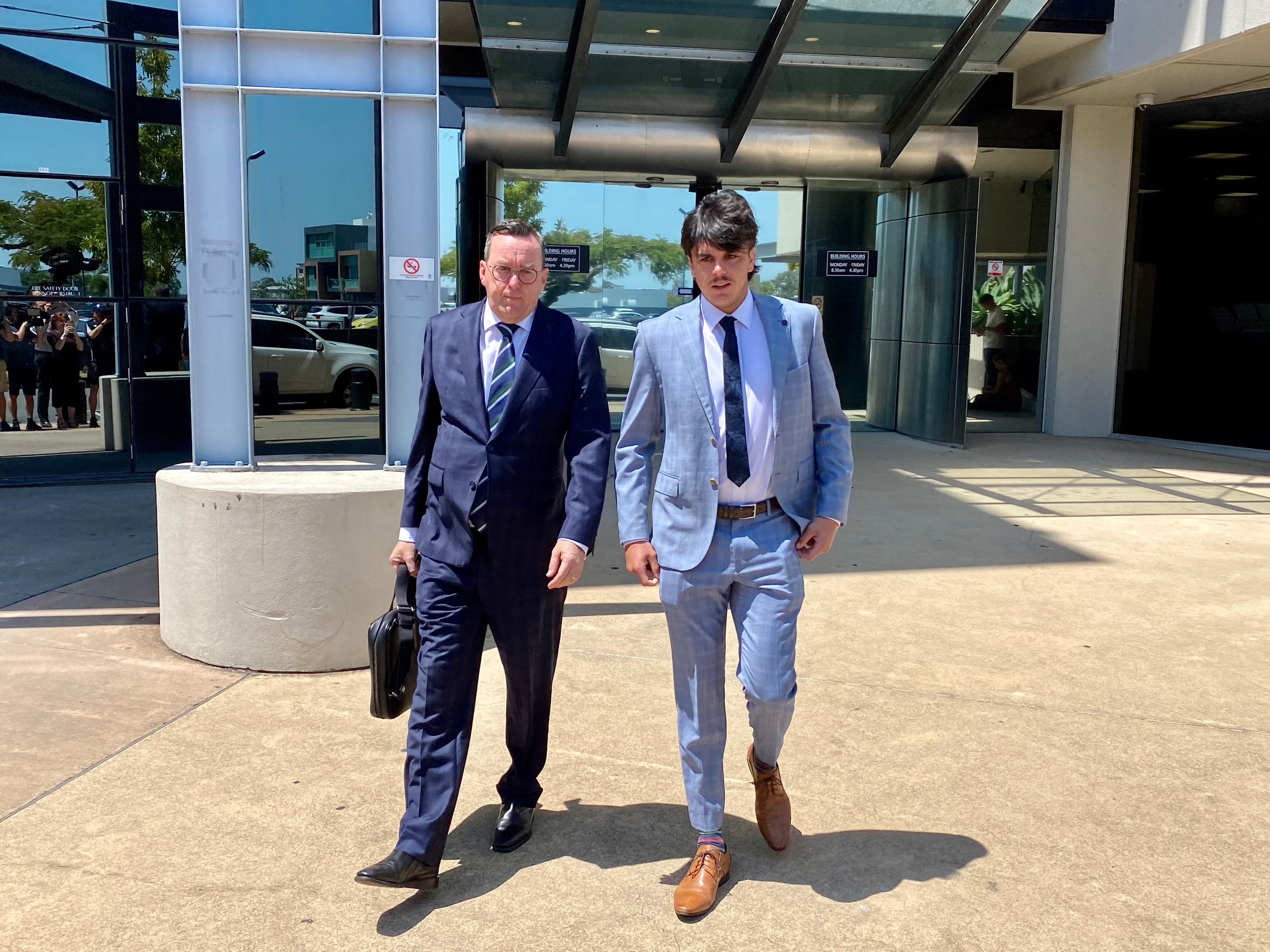 AFL Elijah Hollands walks from a courthouse with his lawyer