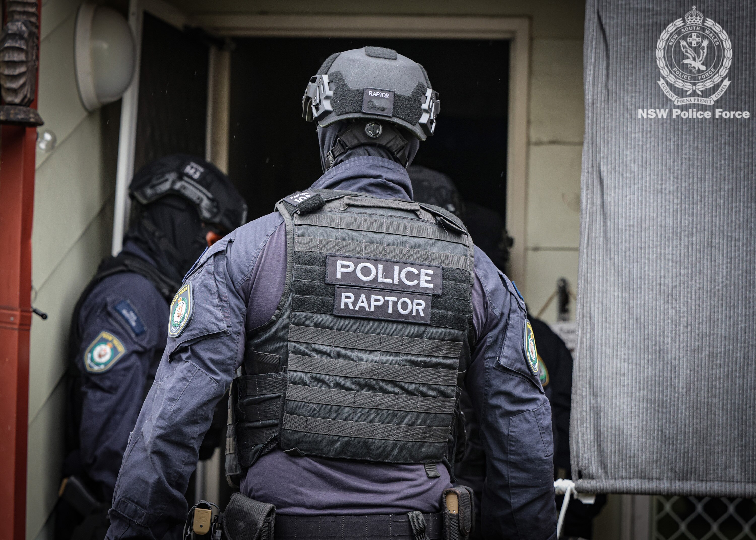 Police officers in raptor uniforms enter a property