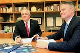 Scott Morrison (left) and Mathias Cormann (right) examine budget documents at Parliament House in Canberra on May 9, 2017.