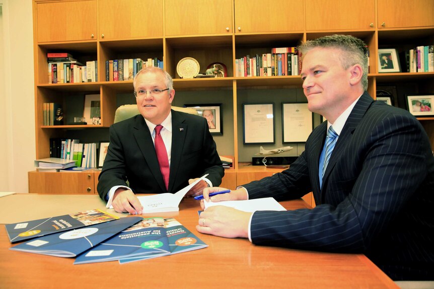 Scott Morrison (left) and Mathias Cormann (right) examine budget documents at Parliament House in Canberra on May 9, 2017.