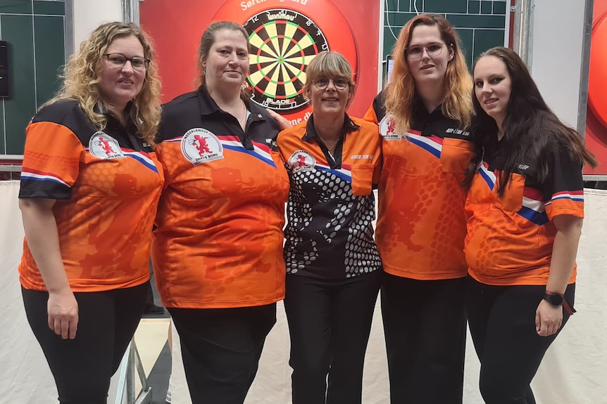 Five women are pictured wearing orange polo's with the Dutch flag on them. 