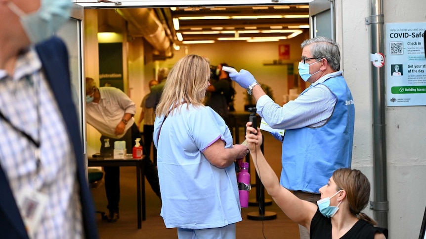 a woman getting her temperature checked outside a hospital