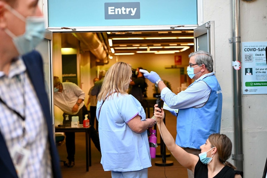 a woman getting her temperature checked outside a hospital