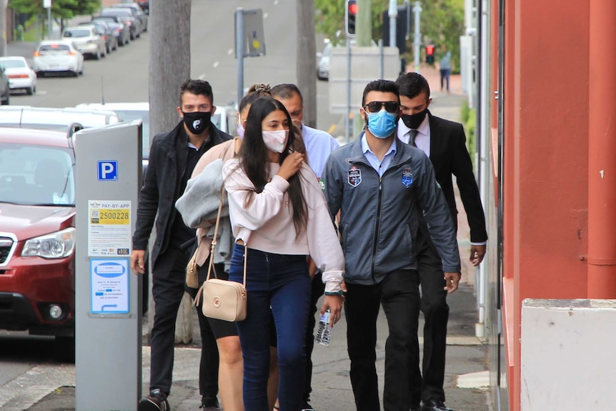 A group of people walking up a path wearing face masks