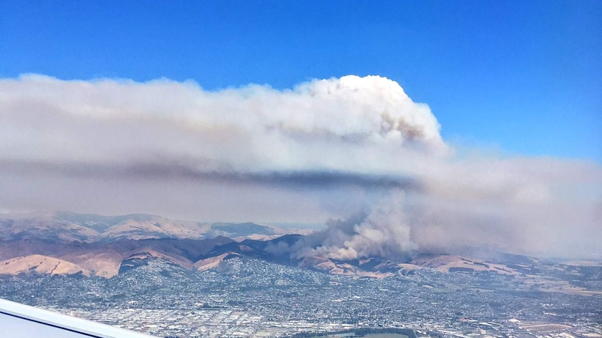 Smoke billows from a fire near Christchurch, as seen from a plane window.