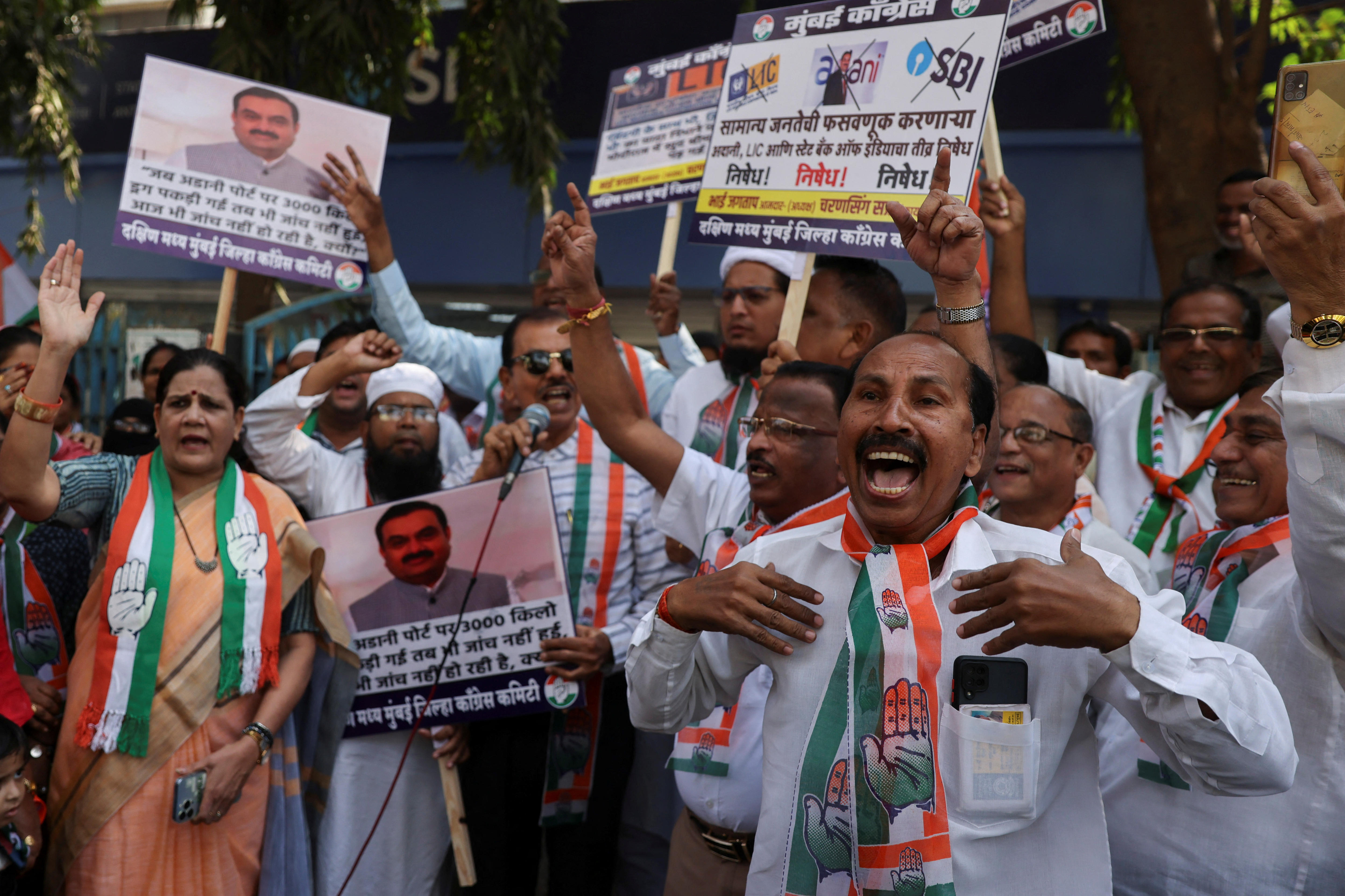 A group of protesters with arms raised, holding up signs