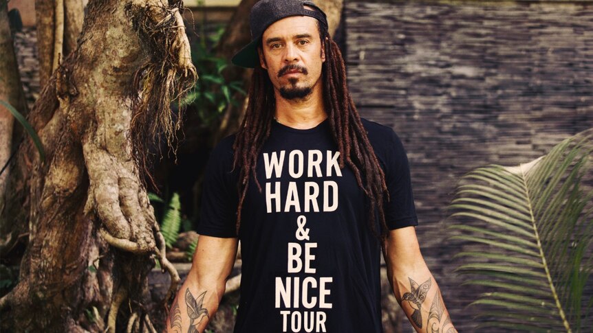 Songwriter Michael Franti wearing a shirt that says work hard and be nice