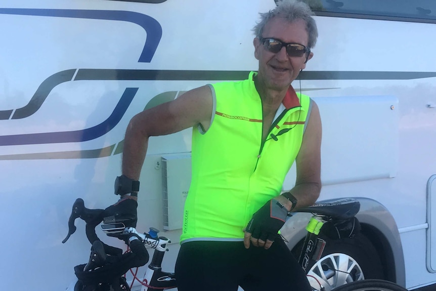 Ross Andrewartha wears a high-vis top and leans against a caravan