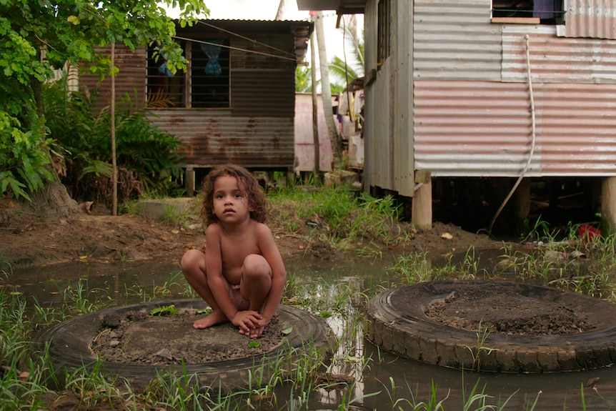 A boy sits on a tyre.