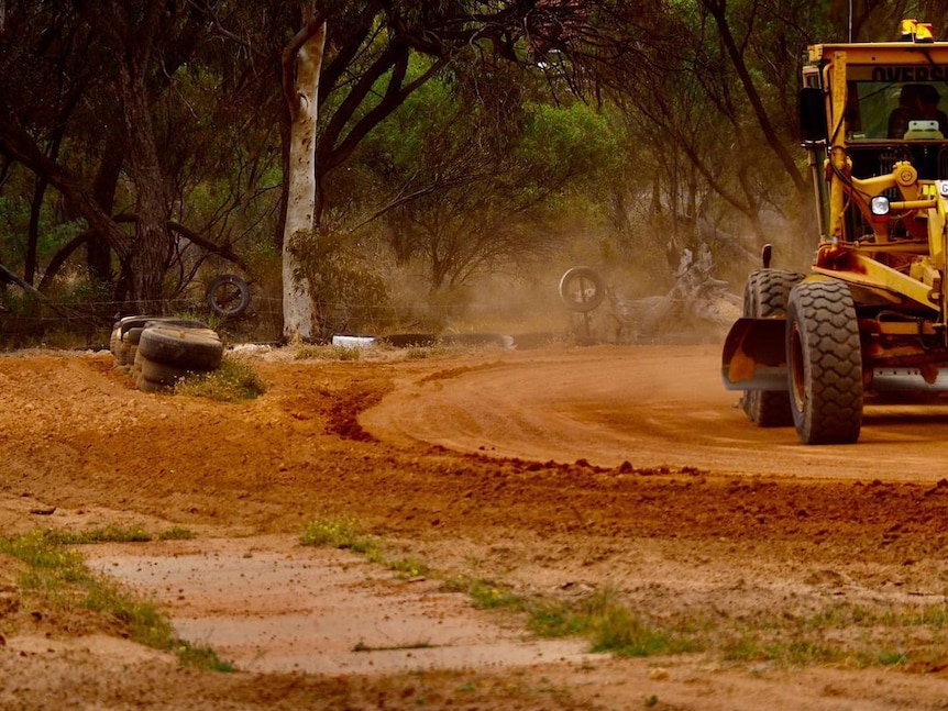 A tractor clears a go-kart track beside an old cement cricket pitch