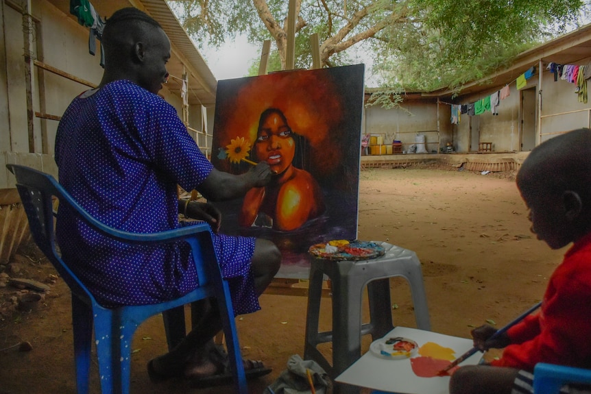 Suleiman Ahmed Abdallh Morgan sits with his son painting 