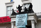 Squatters hang a banner saying "this property has been liberated" from a mansion balcony.
