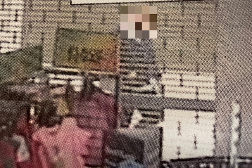 A CCTV image of a person with their face blurred.