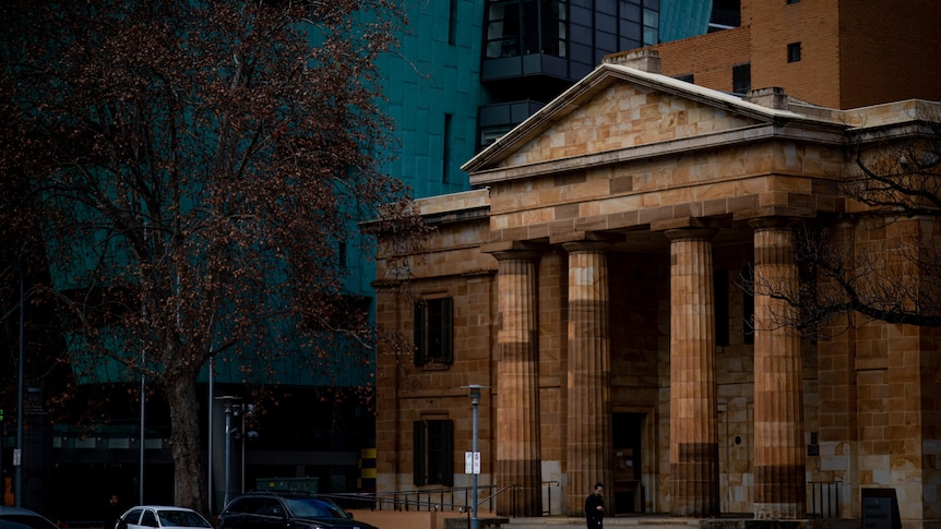 A court build with a columned verandah and a blue coloured building behind