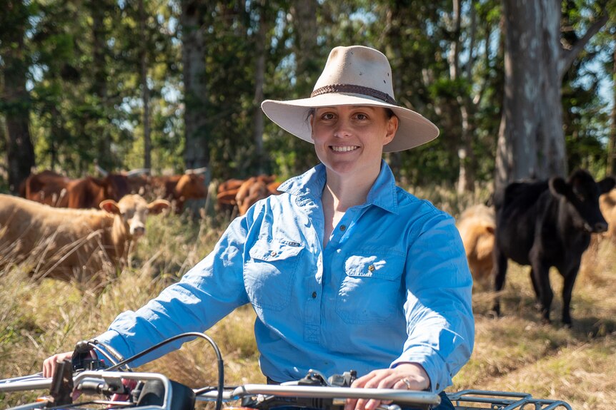 Caitlin McConnel sitting on a motorbike with cattle in the background, Toogoolawah, Queensland, July 2020.