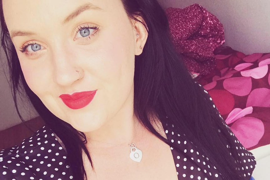 A selfie head and shoulders shot of Olivia Mead wearing a polka dot dress and red lipstick with black hair.