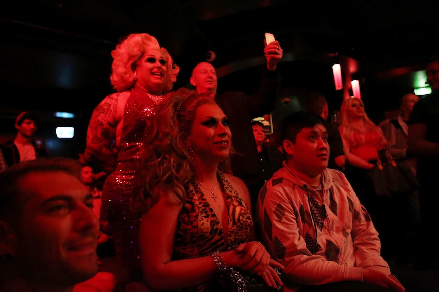 Conchita Grande watches her fellow performers on stage with pride from the audience.