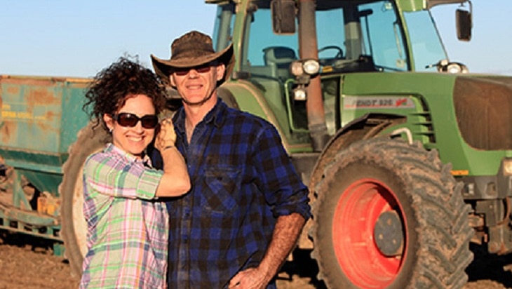 A man and a woman standing in front of a tractor.