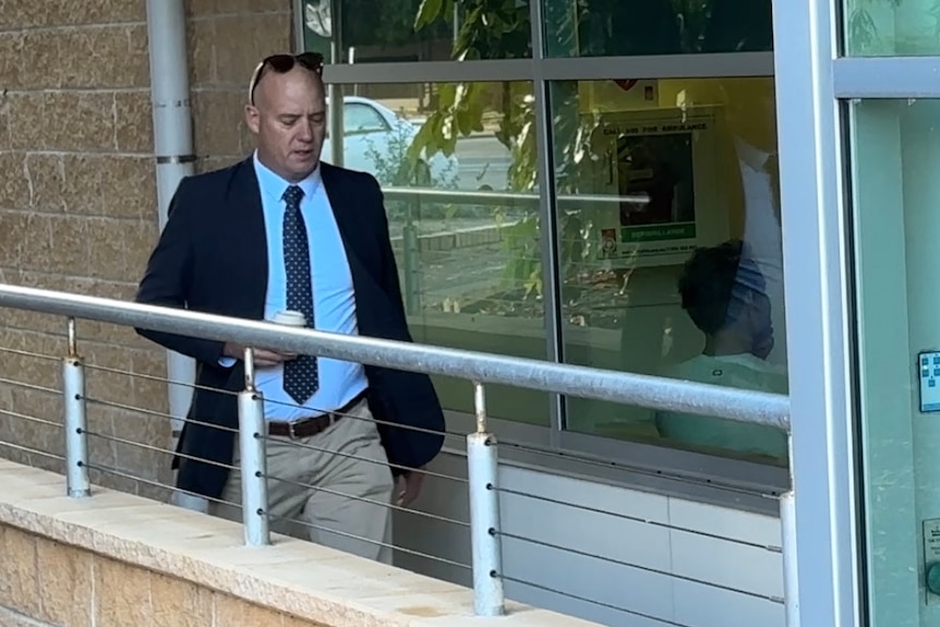 A man walking in front of a court house. 