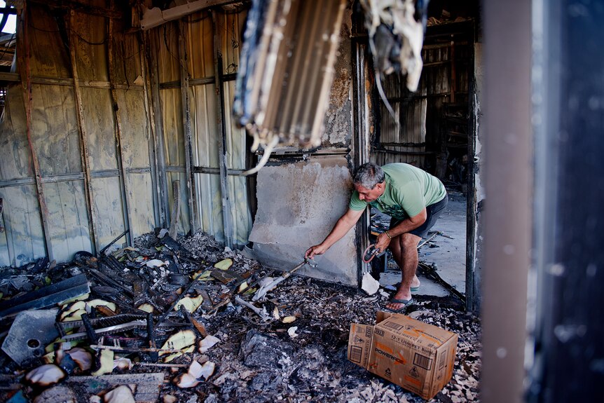 Kerry Kyriacou looks through what remains of his joinery business after a fire gutted the building.