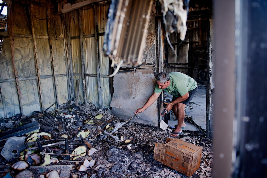 Kerry Kyriacou looks through what remains of his joinery business after a fire gutted the building.