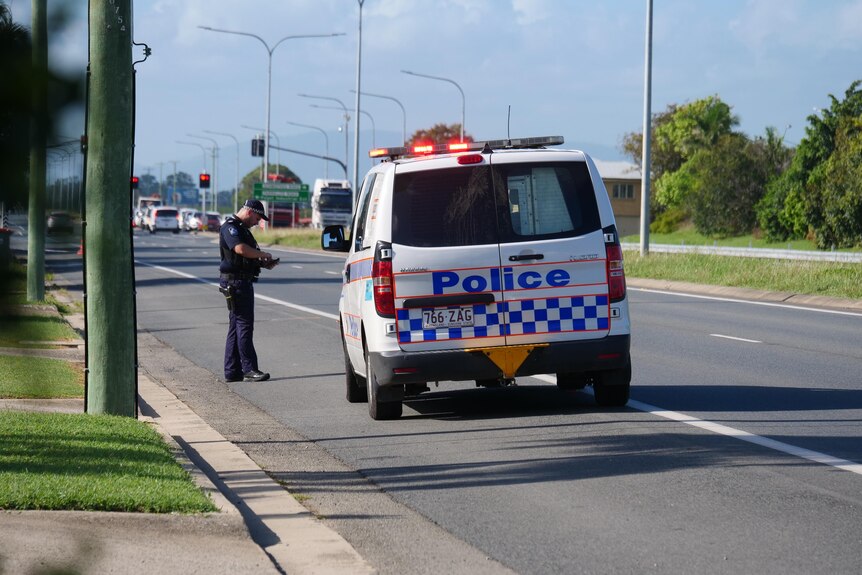 A police van parked on the side of the Bruce Highway, with an officer standing in front of the van