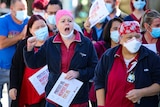 Crowds of health workers in uniform and masks holding signs.