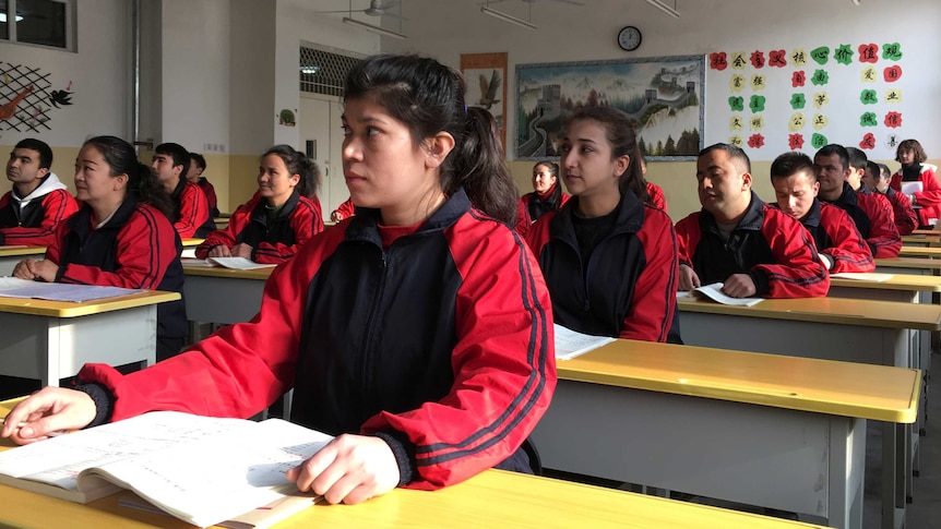 Men and women in matching outfits sit in a classroom.