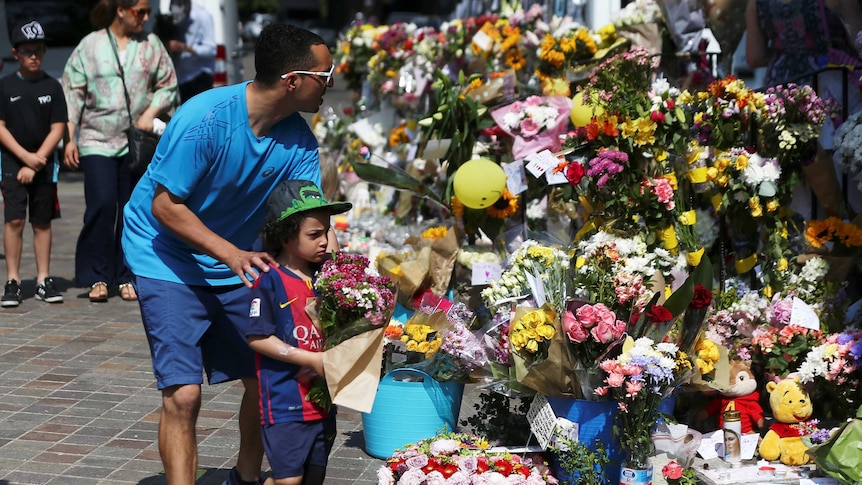 A man helps a boy leave flowers next to other tributes left for the victims of the Grenfell tower fire.