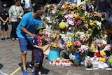 A man helps a boy leave flowers next to other tributes left for the victims of the Grenfell tower fire.