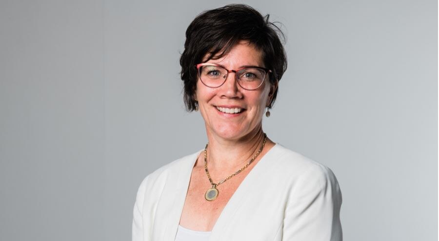 a woman wearing glasses looking at the camera and smiling