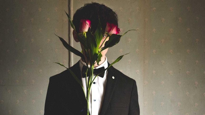 man holding roses in front of his face