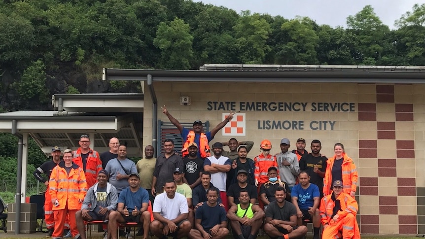 A group of Fijians and SES staff, some in orange jumpsuits, in front of an Emergency Service building.