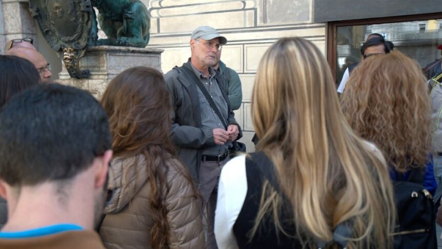 A tour guide stands in front of a crowd of people.