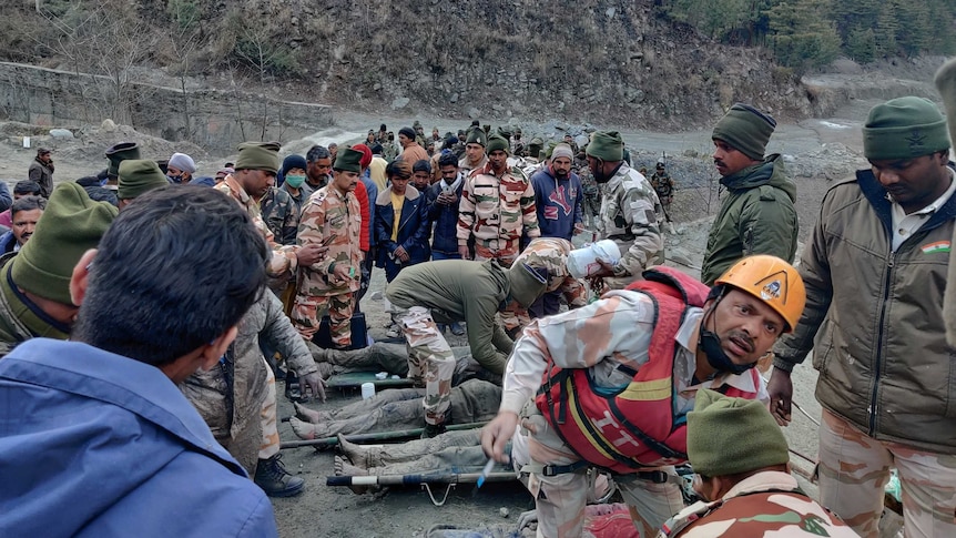 Rescuers tend to people who are covered in mud and laid on stretchers.