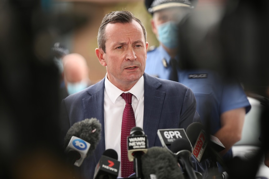 Mark McGowan surrounded by cameras and microphones.