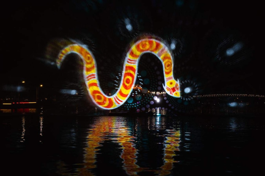 A light projection on Elizabeth Quay in Perth shows the image of a Rainbow Serpent