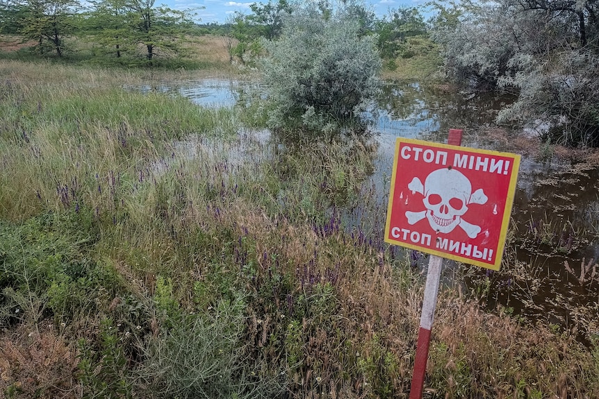 A mine danger sign is seen near a flooded area after the Nova Kakhovka dam breached.