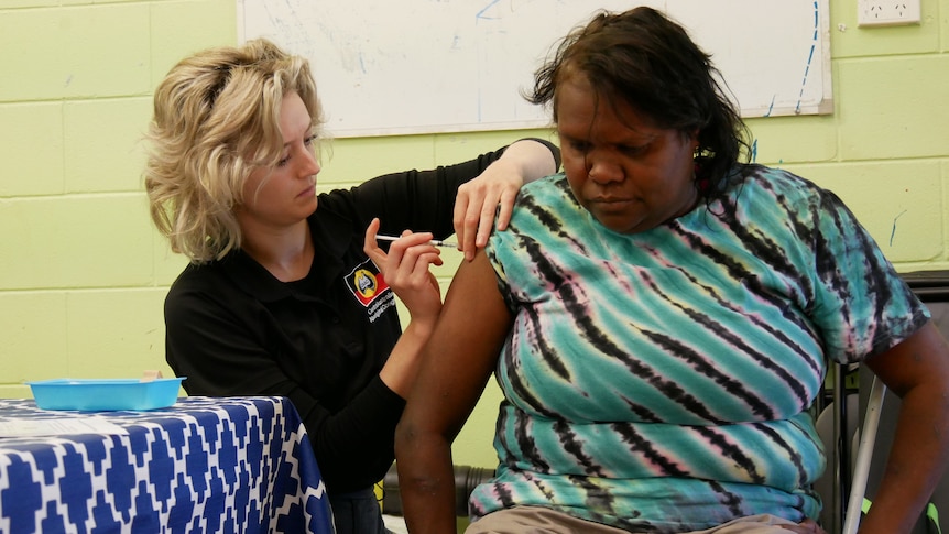 nurse gives Indigenous woman coronavirus vaccine