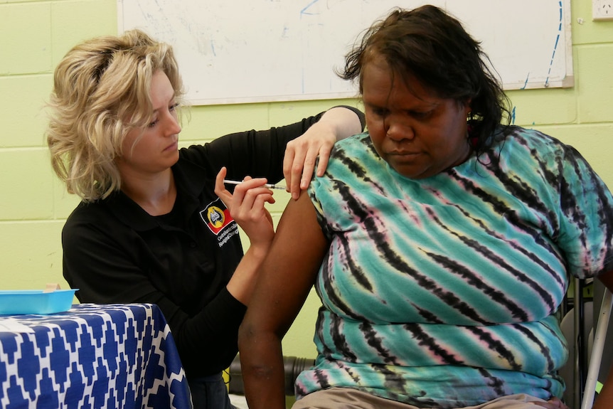 nurse gives Indigenous woman coronavirus vaccine