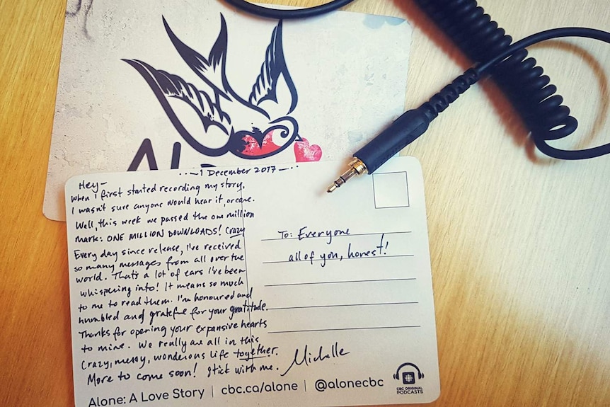 A written postcard  and headphone lead on a desk.