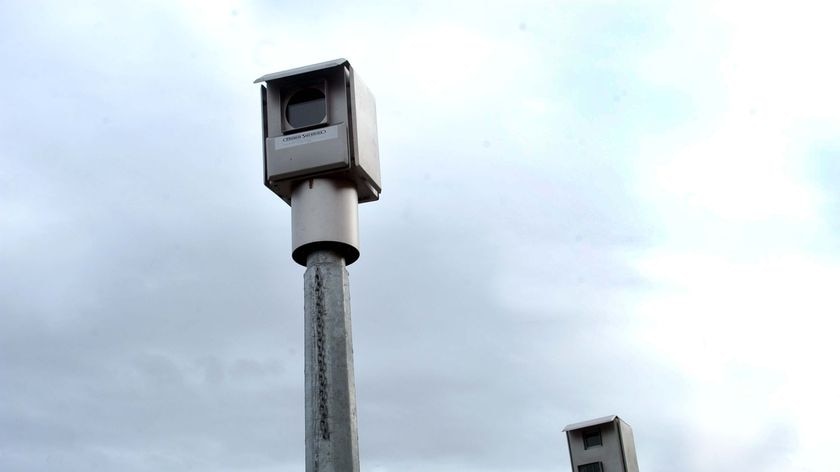 A red light camera sits by the side of the road