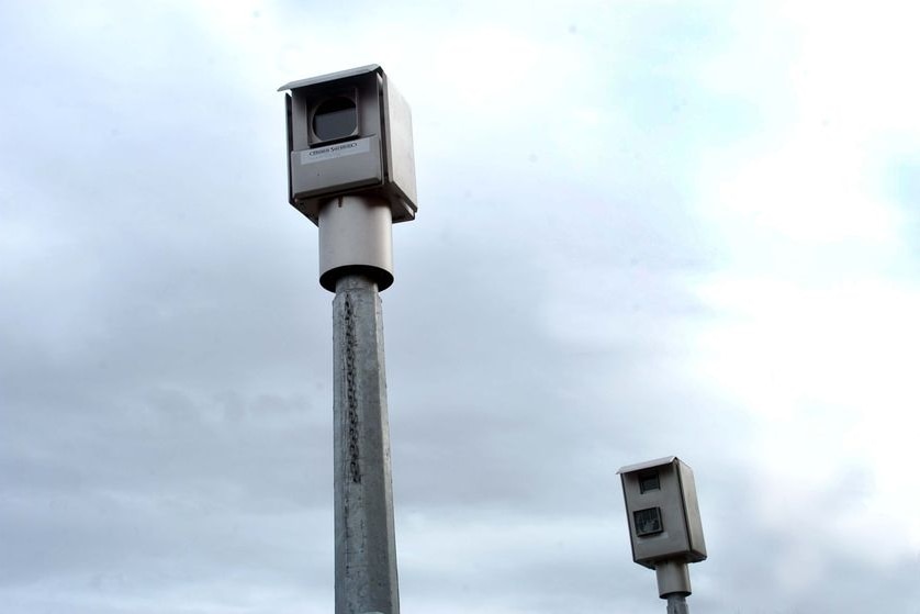 A red light camera sits by the side of the road