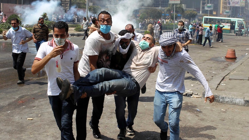 Supporters of deposed Egyptian President Mohammed Morsi carry a protester injured during clashes.