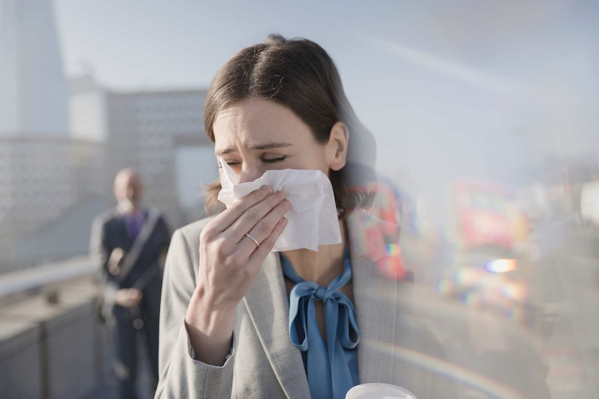 Young women in business clothes blows nose.