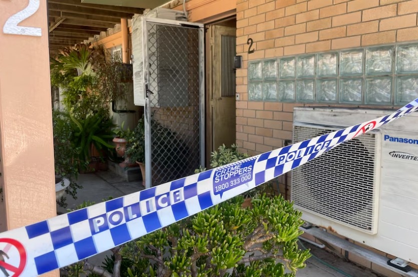 Police tape cordones off a pathway at a brick aparment building.