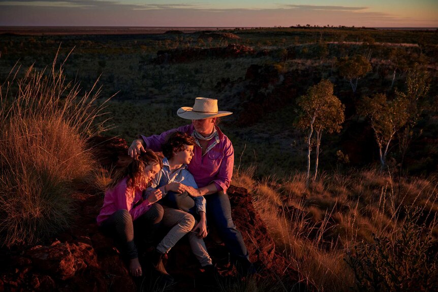 Jane Sale sits with her two children watching the sunset over a Kimberley outcrop