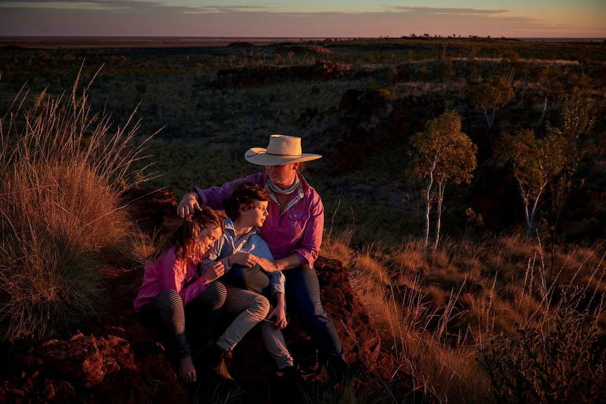 Jane Sale sits with her two children watching the sunset over a Kimberley outcrop