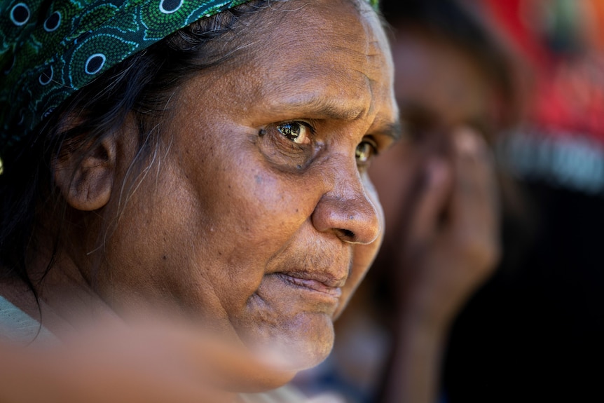 An Indigenous grandmother looks distraught as she is pictured side on