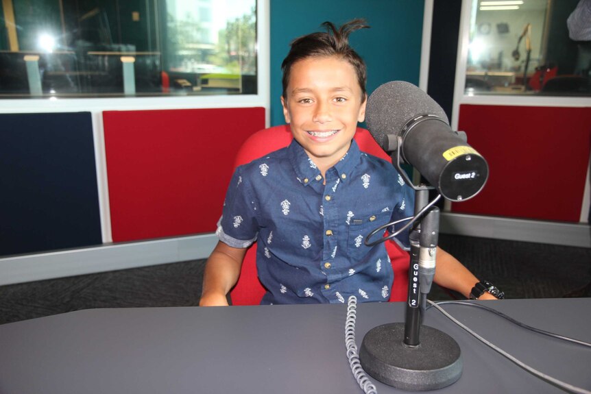 A young boy in a radio studio behind a microphone.